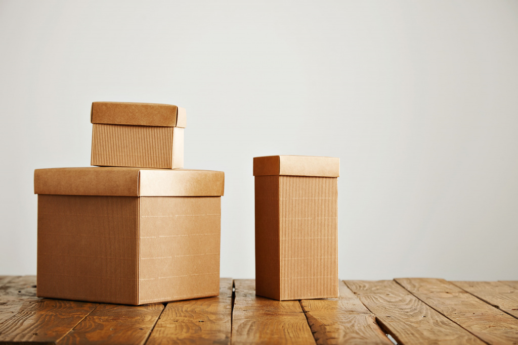 three-different-sized-beige-cardboard-boxes-arranged-top-brown-rustic-table-studio-with-white-walls.jpg